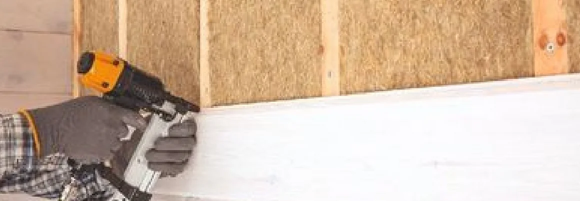 Person befestigt Holzpaneel mit Druckluftnagler